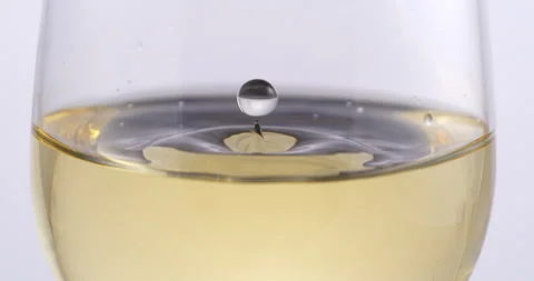 White wine drop falling with splashes in transparent glass in wine cellar Stock Footage 268801540