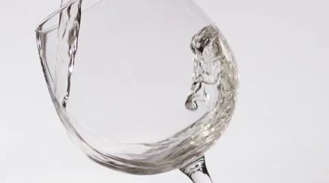 White wine flows in a glass on a white background slow motion Stock Footage 65277115