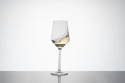 White wine movement inside a crystal glass. white wine glass on white background Stock Photos