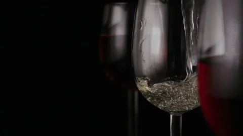 White wine is poured into one of the three glasses Stock Footage 74877856