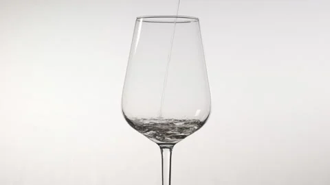 White wine poured into a wine glass. Slow motion on a white background. Stock Footage