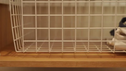 White Wire Basket Offers Practical Storage on Wooden Shelf Stock Footage 318784602