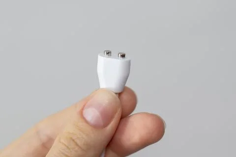 A white wire with two round magnets in a woman's hand. Magnetic charger for Stock Photos