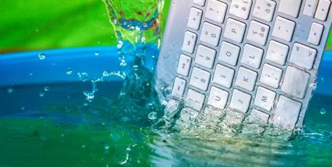 White wireless computer keyboard falling into the water spraying Stock Photos