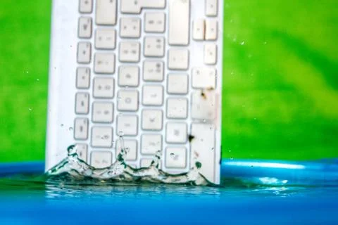 White wireless computer keyboard falling into the water spraying Stock Photos