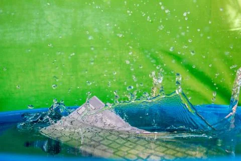 White wireless computer keyboard falling into the water spraying Stock Photos