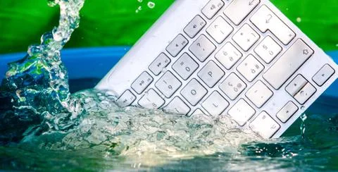 White wireless computer keyboard falling into the water spraying Stock-Fotos