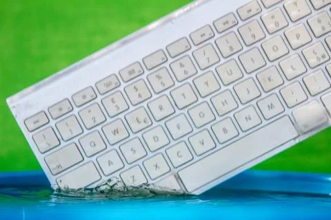 White wireless computer keyboard falling into the water spraying Foto stock