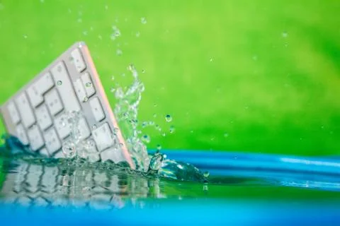 White wireless computer keyboard falling into the water spraying Stock Photos