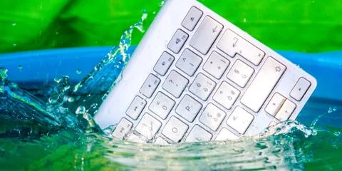 White wireless computer keyboard falling into the water spraying Stock Photos