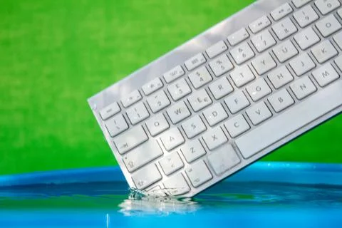 White wireless computer keyboard falling into the water spraying Foto stock