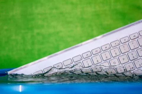 White wireless computer keyboard falling into the water spraying Foto stock