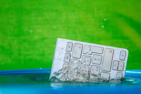 White wireless computer keyboard falling into the water spraying Stock Photos