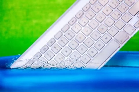 White wireless computer keyboard falling into the water spraying Stock Photos