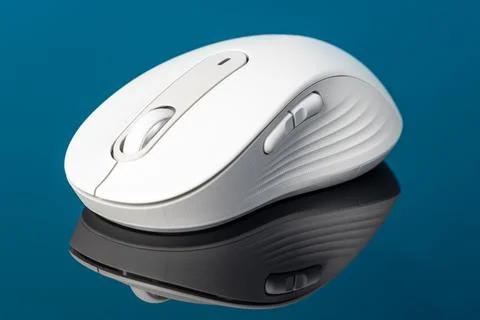 White wireless computer mouse with reflection on blue background, modern er.. Stock Photos