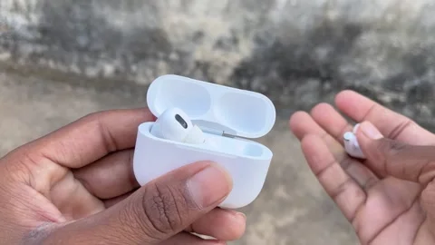 White Wireless Earbuds Being Placed Back Into an Empty Charging Case Видео 321674312