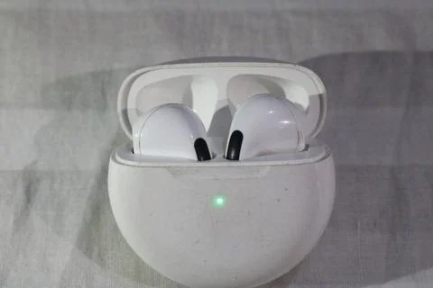 White wireless earbuds in charging case with green light on fabric backgrou.. Stockfoto's