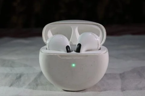 White wireless earbuds in open charging case on gray surface  technology 写真素材
