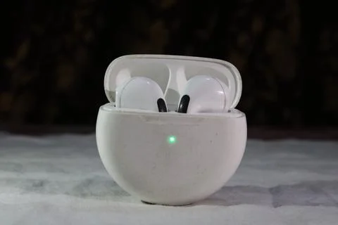 White wireless earbuds in open charging case on gray surface  electronic devi 写真素材