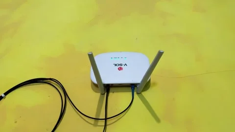 White Wireless Router with Blinking LED Lights Connected Cables on a Yellow Wall Video stock 346159336