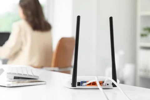 White wireless router with ethernet cables connected on a desk in a modern of Stock Photos