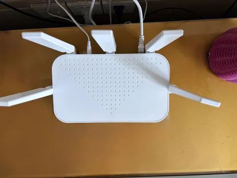 White Wireless Router with Multiple Antennas on Wooden Desk Foto stock