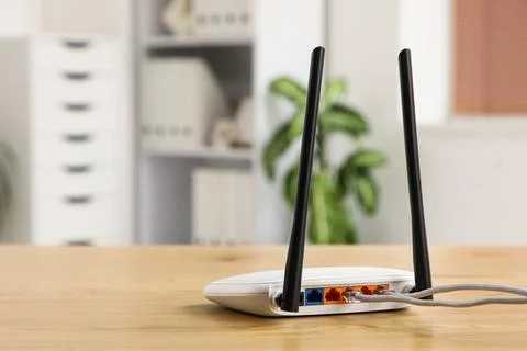 White wireless router with two antennas and connected ethernet cables on a wo Stock Photos