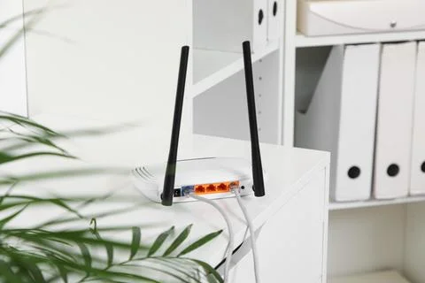 White wireless router with two antennas and connected ethernet cables on a de Stock Photos