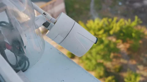White Wireless Security Camera Mounted on Window Ledge with Diy Housing Stock Footage 338100829