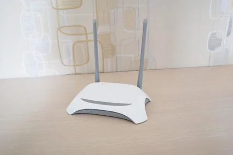 White wireless Wi-Fi router with dual antennas sitting on a wooden surface .. Stock Photos