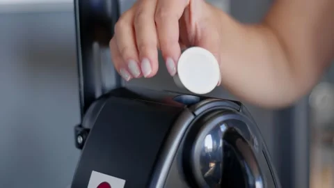 White woman's hand inserts organic compostable espresso capsule into Nespresso Stock Footage 143968122