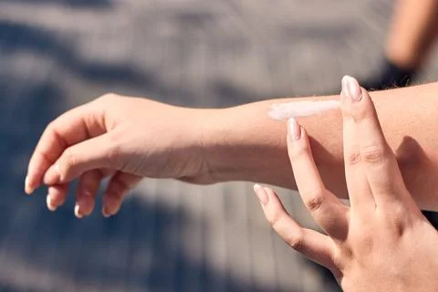 A white woman's hands, applying white beauty and skincare cream to her arm Stock Photos