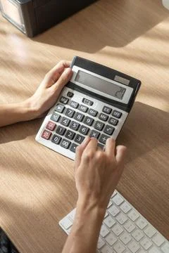 White woman's hands using a calculator on wooden table Stock Photos