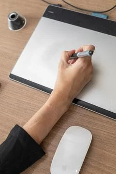 White woman's hands using computer pen on a wooden table Stock Photos