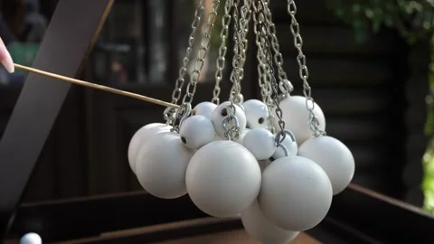 White wooden ball pendulum game with metal chains outdoors Stock Footage 332411276