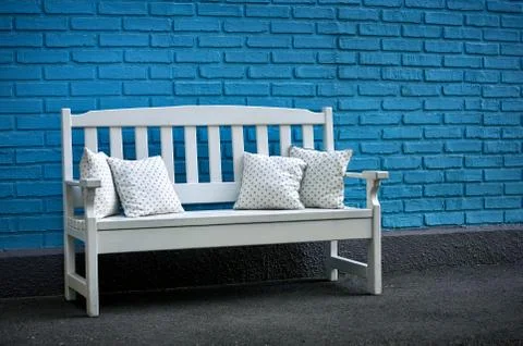 White wooden bench with pillows on blue brick wall background Stock Photos