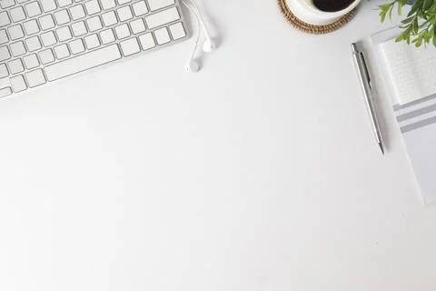 White working desk with notebook, coffee cup, keyboard and potted plant. To.. Stock Photos