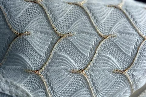 White woven fabric with an pattern of white and fine gold threads. Stock Photos