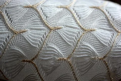 White woven fabric with an pattern of white and fine gold threads. Stock Photos
