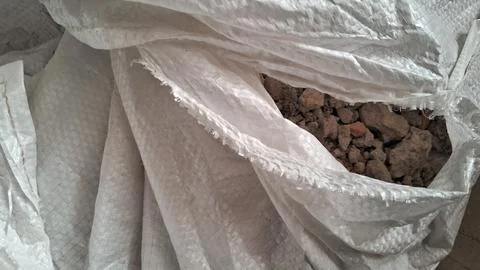 White woven polypropylene sack filled with rough brown construction rubble Stock Photos