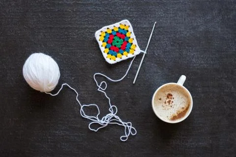 White yarn, crocheted multi-colored motif and coffee Stock Photos
