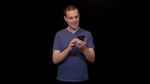 White young Man on black background scrolling on his phone and typing Mid shot Vidéo 146116692