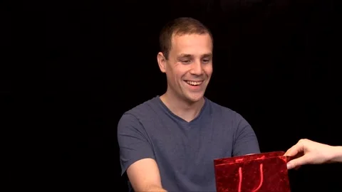 A white young Man on black background receives a present Vidéo 146263744