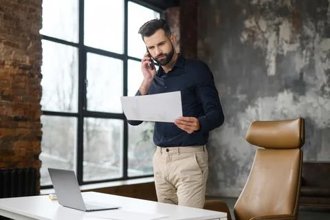 Whitecollar worker on laptop gesturing while holding paper Foto stock