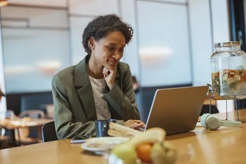 A whitecollar worker sits at a table using a laptop computer Stock Photos