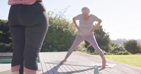 Whitehaired senior stepping onto mat doing leg lifts on deck building balance Stock Footage 343367803