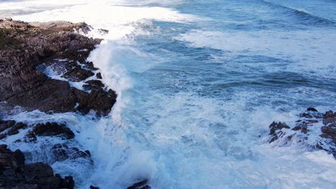 Whitewash created on shoreline as ocean waves surges against jagged rocks. Stock Footage 245354403