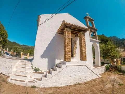 Whitewashed chapel with bell tower under blue sky. Stock Photos