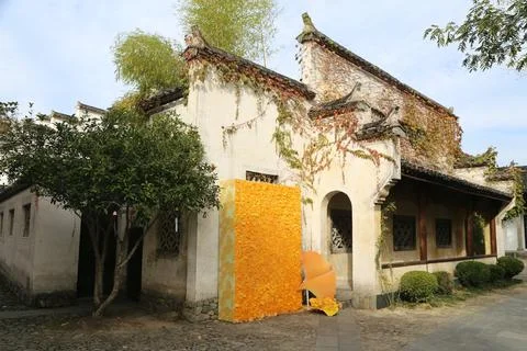 Whitewashed vine covered house with a large yellow decorative panel by the .. 库存照片