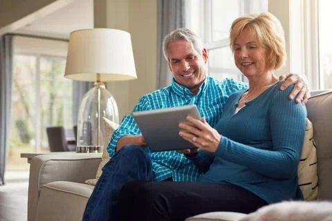 Who knew technology would simplify life so much. a happy mature couple relaxing Stock Photos